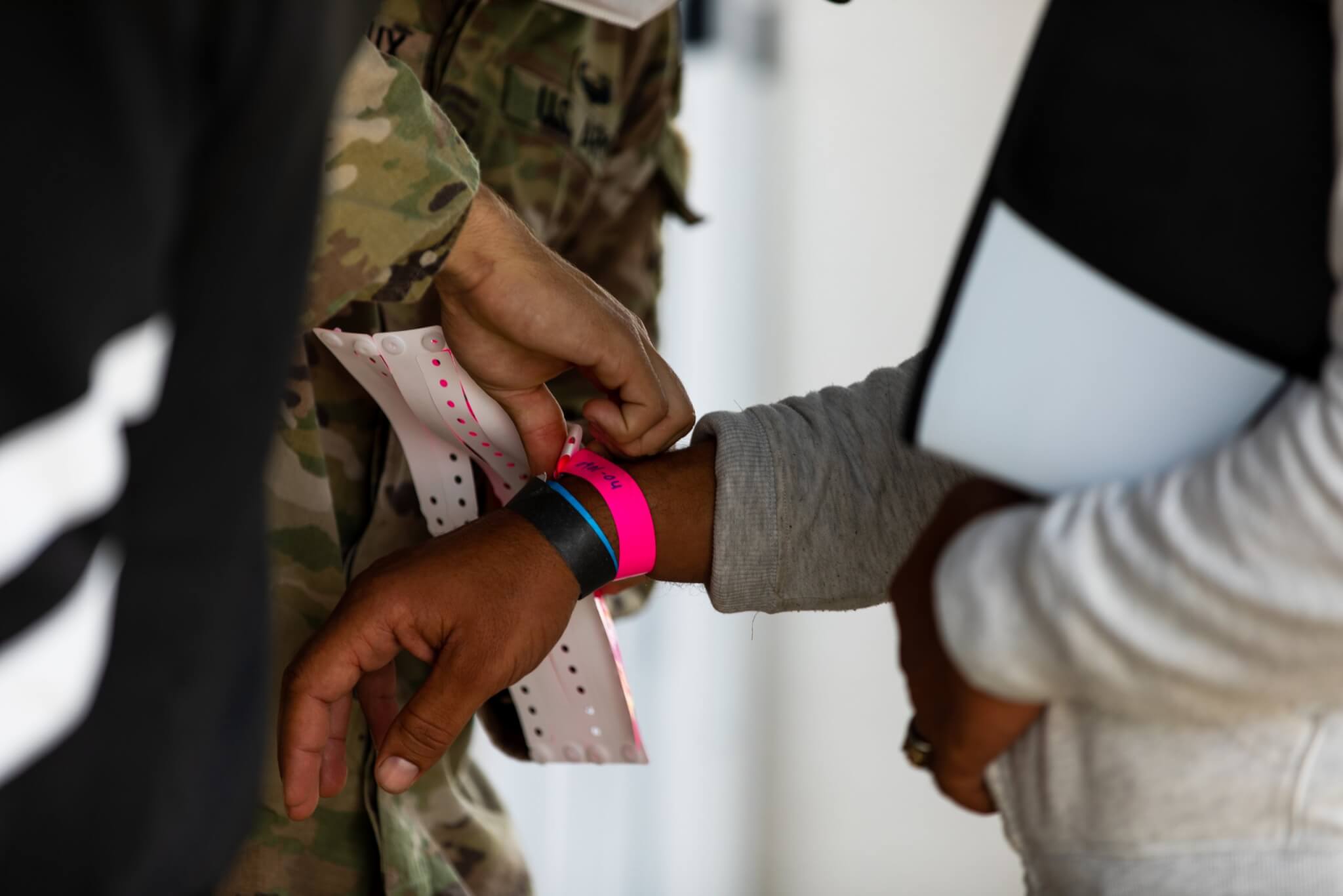 Pfc. Julian Arceneaux, 1st Battalion, 506th Infantry Regiment, places a wristband on an Afghan evacuee, which allows medical teams and State Department representatives to track how far along the Afghans are within their Special Immigrant Visa (SIV) process during Operation Allies Welcome at Fort Pickett, Virginia, Sep. 1, 2021. Photo by SPC Froylan Grimaldo / 7th Mobile Public Affairs Detachment