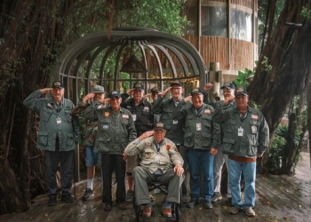 Vietnam War veterans in salute while staring at the camera.