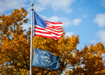American flag flies on flagpole with a Columbia College flag beneath it.