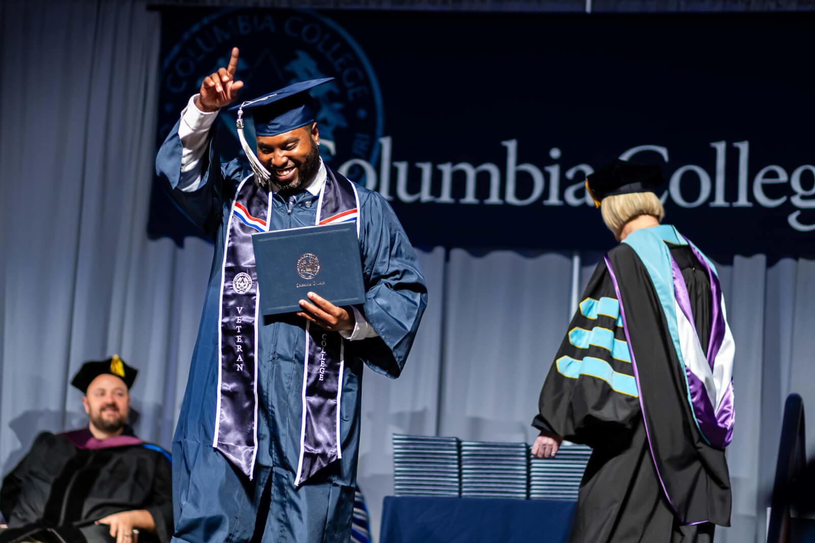 A veteran and Columbia College graduate walks across the stage with his diploma.