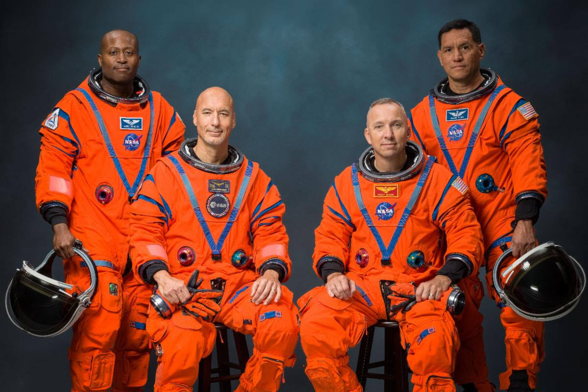 Artemis III crew dressed in orange astronaut suits.