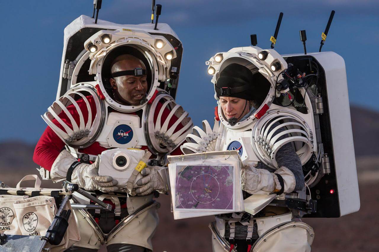 NASA astronauts Andre Douglas and Kate Rubins are in full astronaut gear as they review traverse plans during a nighttime simulated moonwalk.